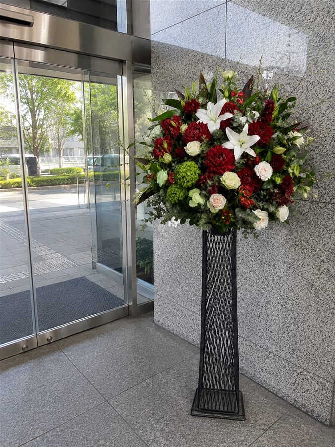 お届け先ビルのエントランス脇に設置したスタンド花のお届け完了報告写真（イメージ）